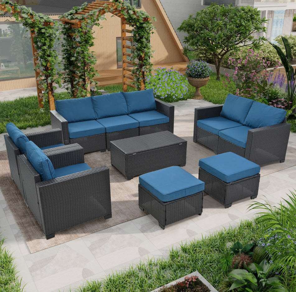 Cozy outdoor patio set with modular wicker seating, blue cushions, coffee table and ottomans on a patio background