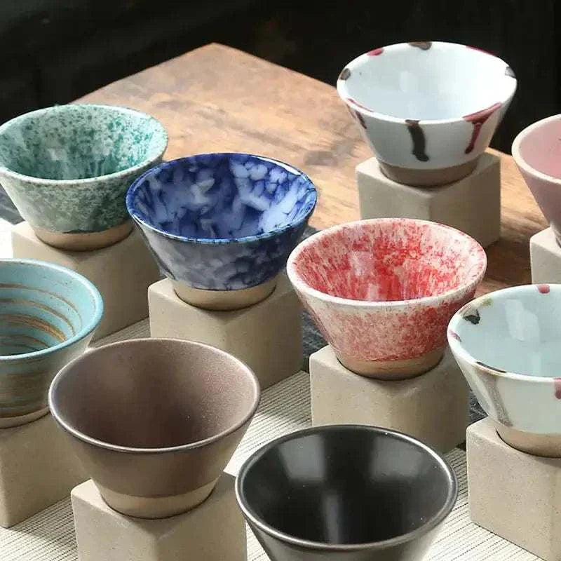 Set of colorful Japanese ceramic bowls displayed on stone stands, showcasing unique patterns and designs.