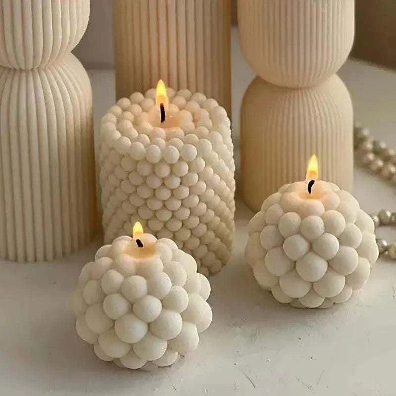 Three unique bubble-shaped candles in creamy white, showcasing a distinctive design, surrounded by decorative columns.