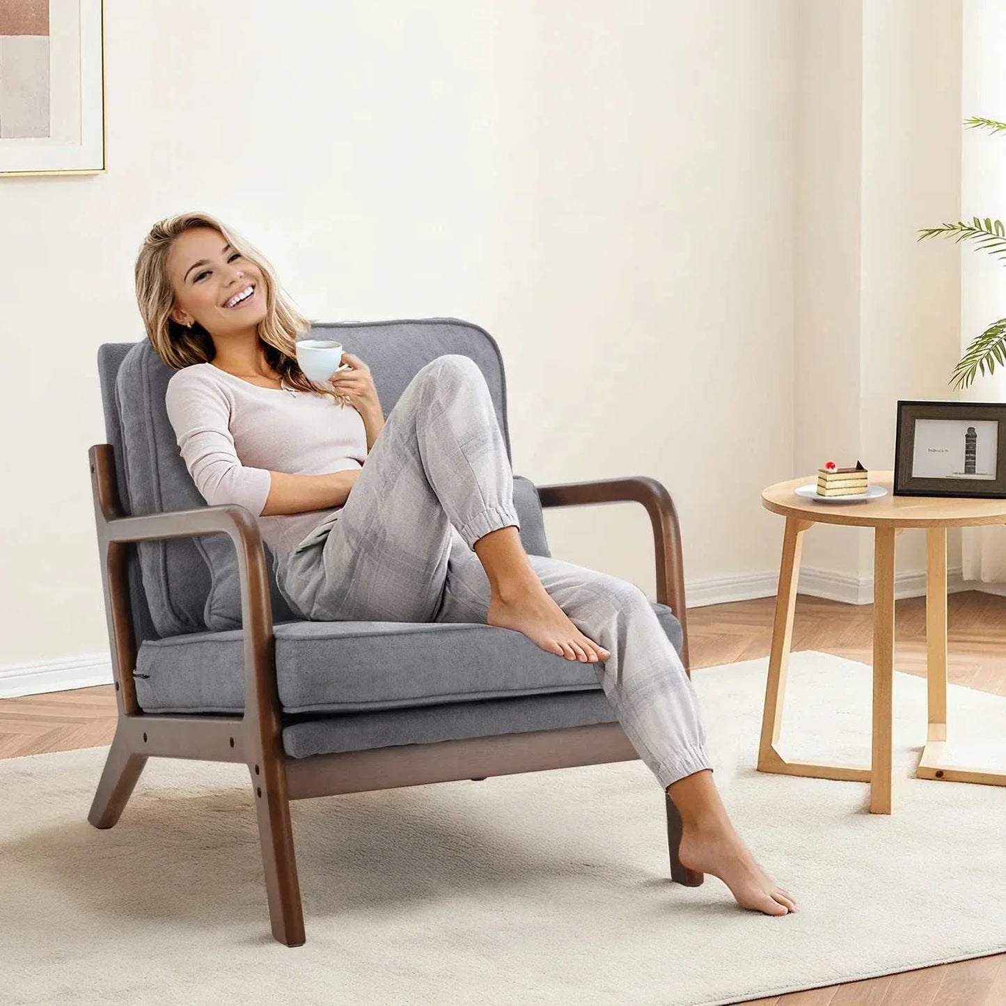 Woman relaxing on a mid century wooden lounge chair with gray cushions in a modern living room