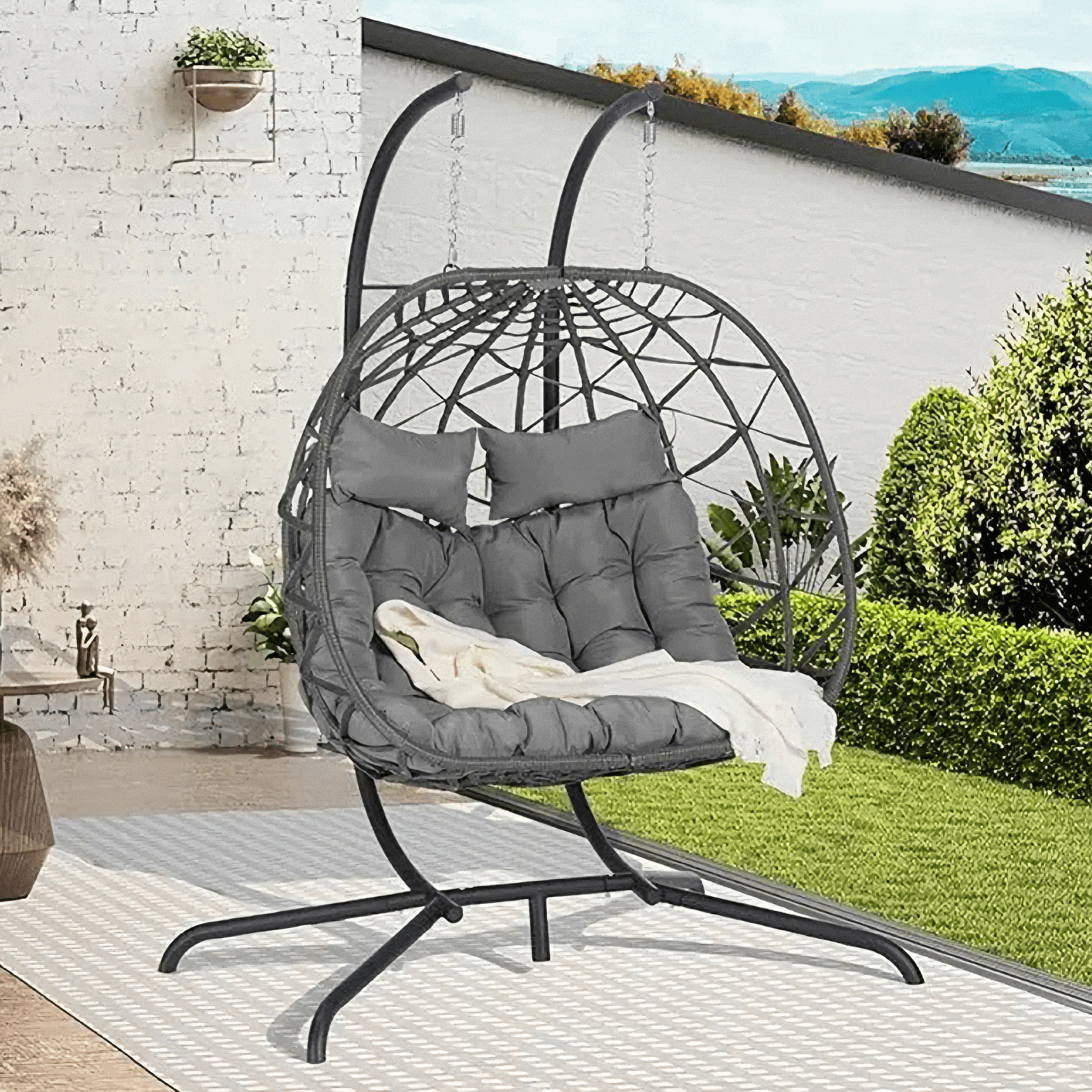 Double Hanging Egg Chair in garden setting, featuring cozy cushions and durable rattan frame for two-person lounging indoors or outdoors.