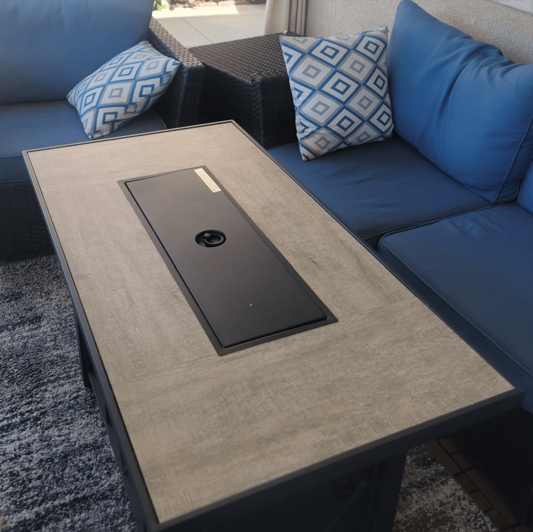Propane Fire Pit Table with black steel frame and cozy couch setting, perfect for outdoor gatherings.