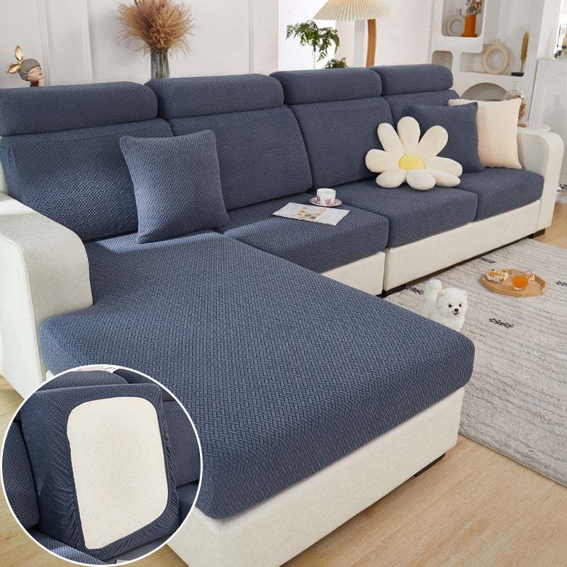 Elastic sofa slipcover in sea blue knitted fabric on modern sectional sofa with decorative pillows and small dog nearby