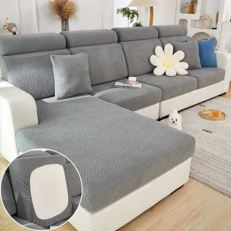 Gray elastic knitted sofa slipcover on modern sectional couch with pillows in living room