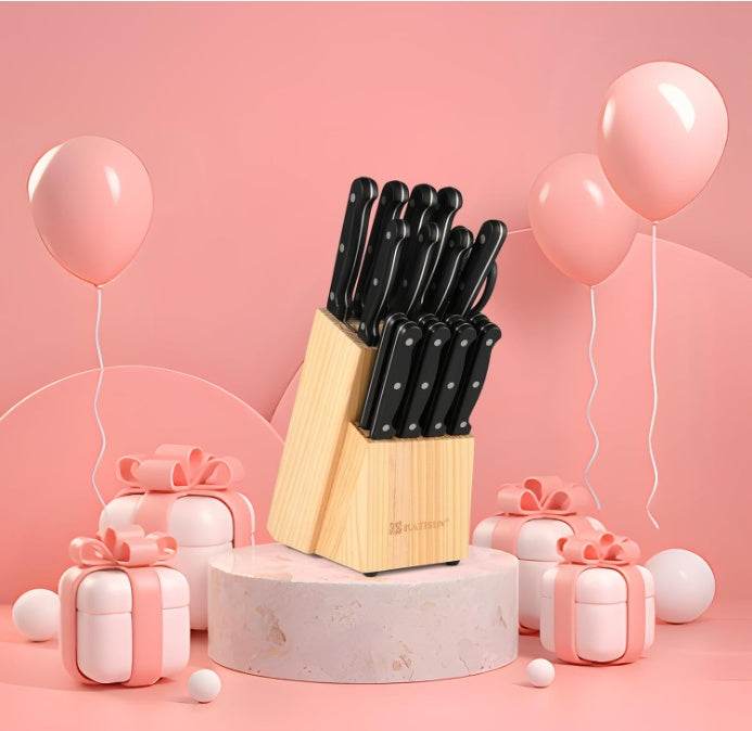 Ultimate German Steel Knife Set with black handles in wooden block surrounded by pink gift boxes and balloons on pink background
