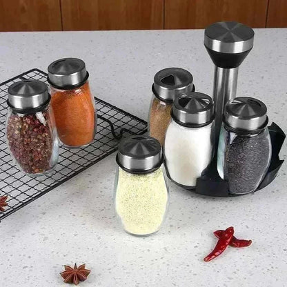 Glass spice rack organizer set with transparent bottles and 360° rotating base, neatly storing spices on a countertop.