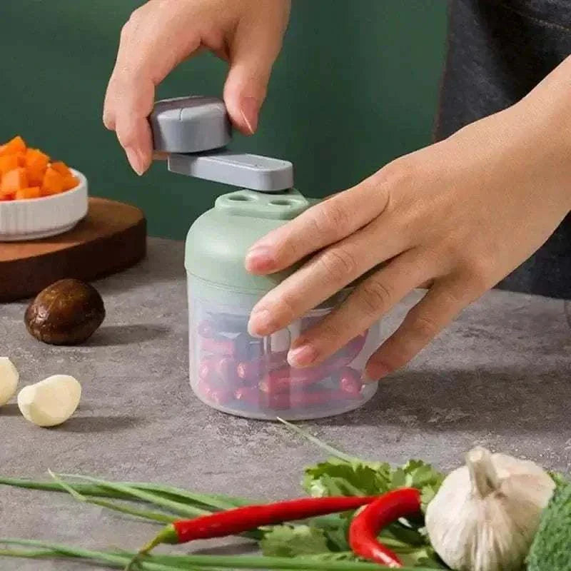 Compact hand-crank food chopper in use, efficiently mincing vegetables on kitchen counter.