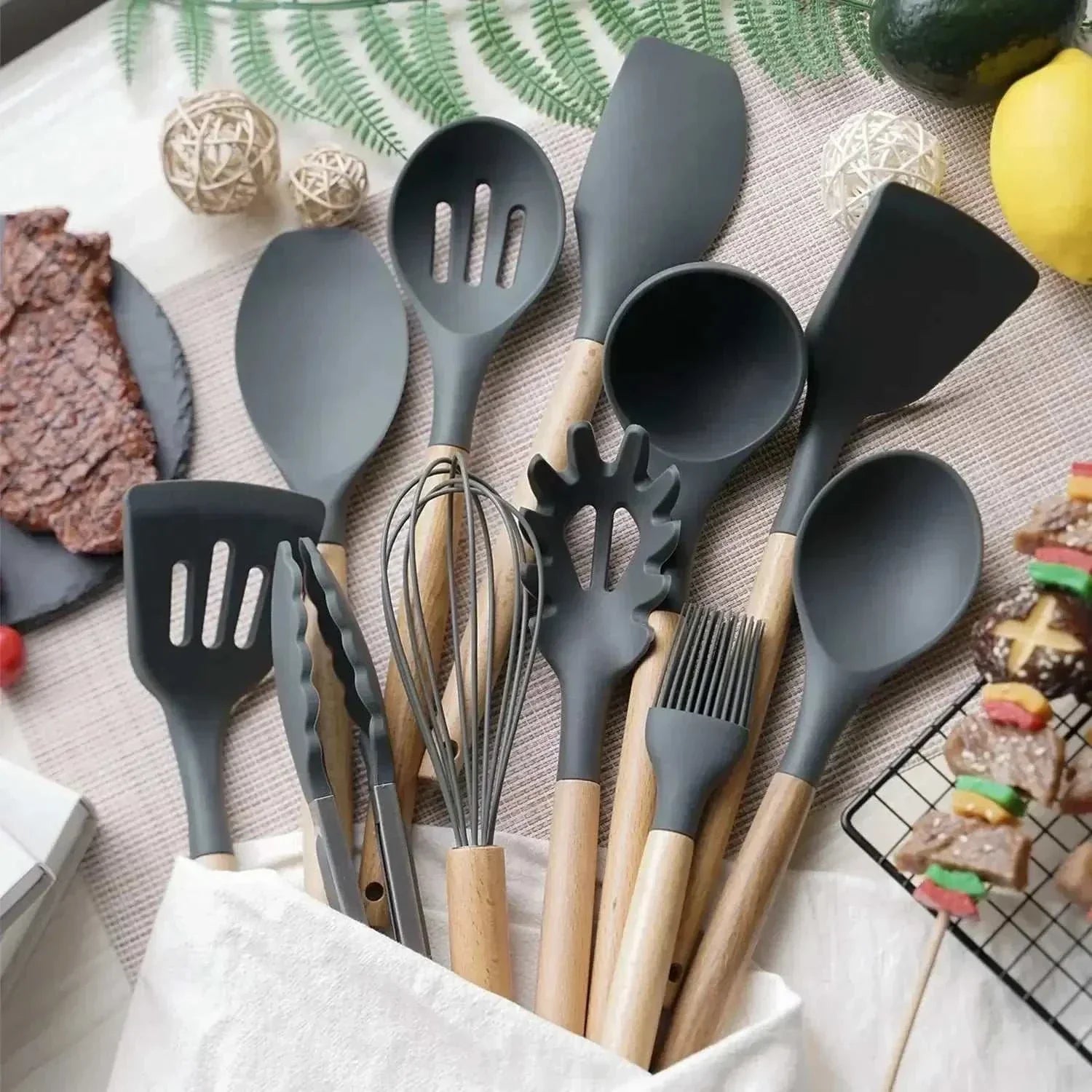 12-piece silicone kitchen tools set with wooden handles, including spatulas, tongs, and whisk, displayed on a countertop.