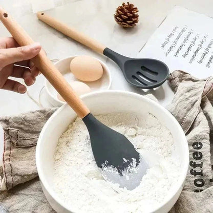 Silicone kitchen tools with wooden handles, used for mixing flour and preparing eggs in a rustic kitchen setting.